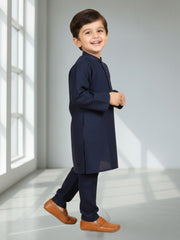 Child wearing a navy kurta with brown shoes in a bright room