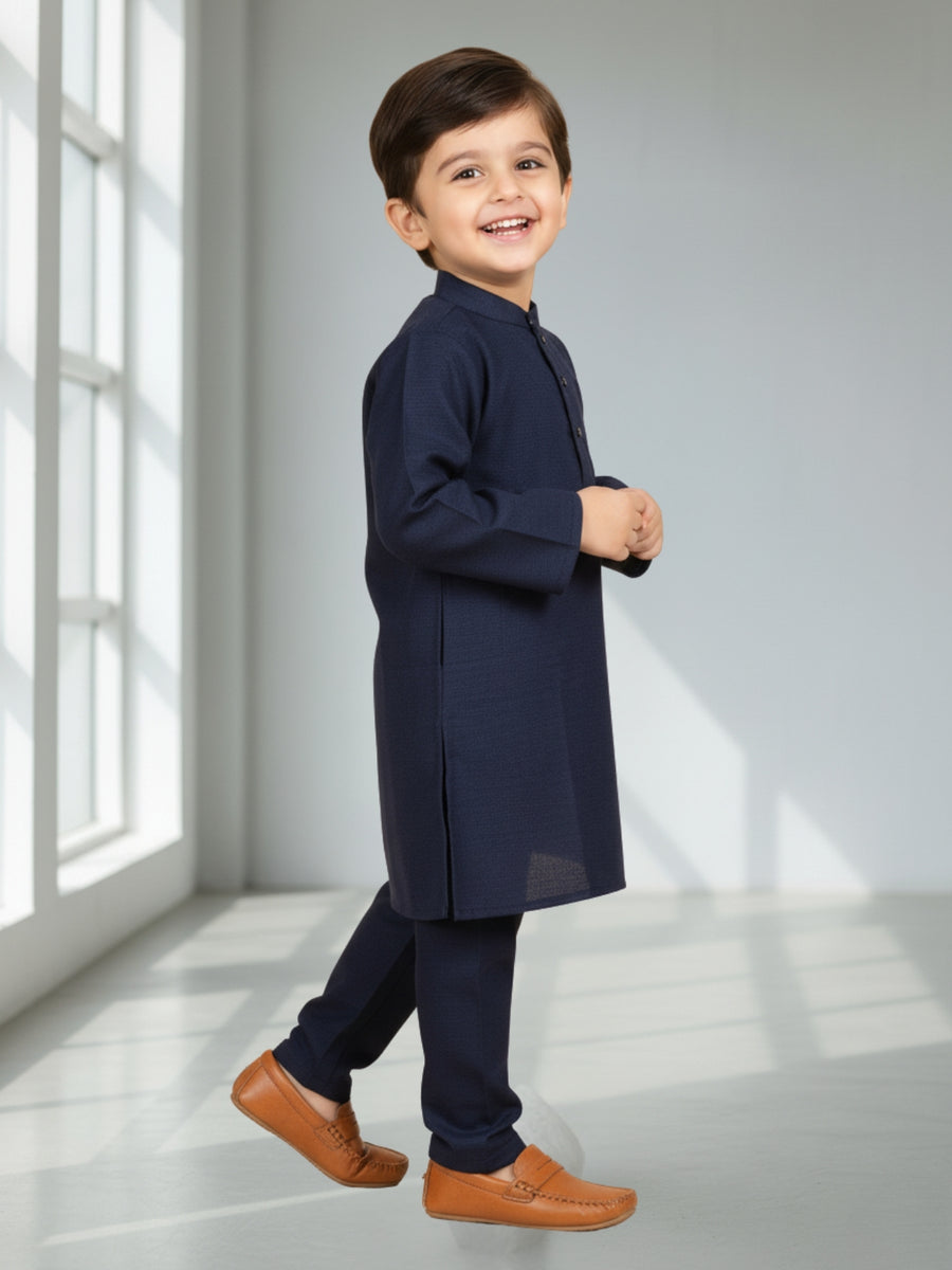 Child wearing a navy kurta with brown shoes in a bright room