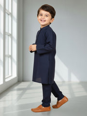 Child wearing a navy kurta with brown shoes in a bright room