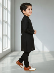 Child wearing a black coat and brown shoes in a bright room with sunlight streaming in.
