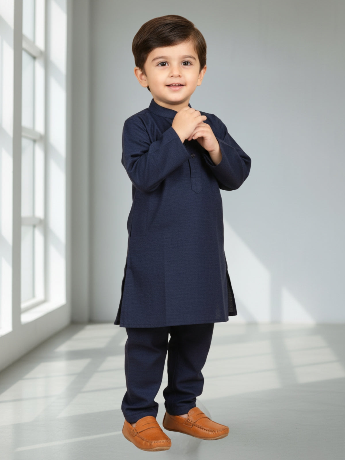 Child wearing a navy kurta with brown shoes in a bright room